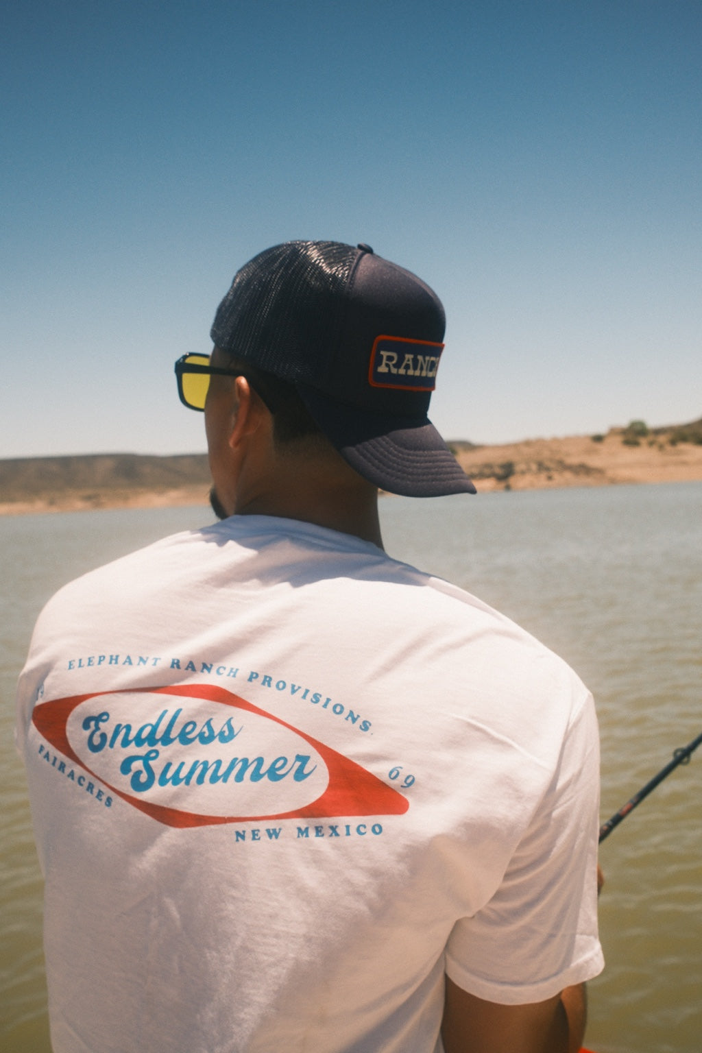 Back view of white Endless Summer Elephant Ranch T-shirt by the lake