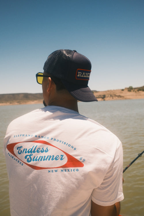 Back view of white Endless Summer Elephant Ranch T-shirt by the lake